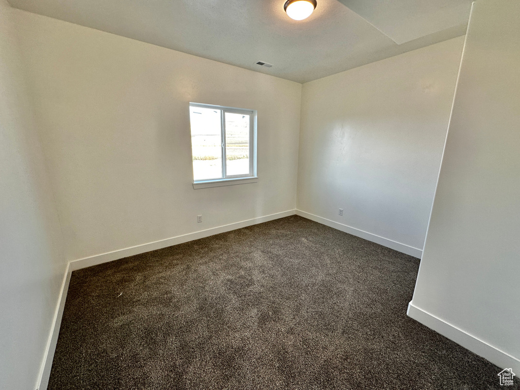 Spare room with dark colored carpet