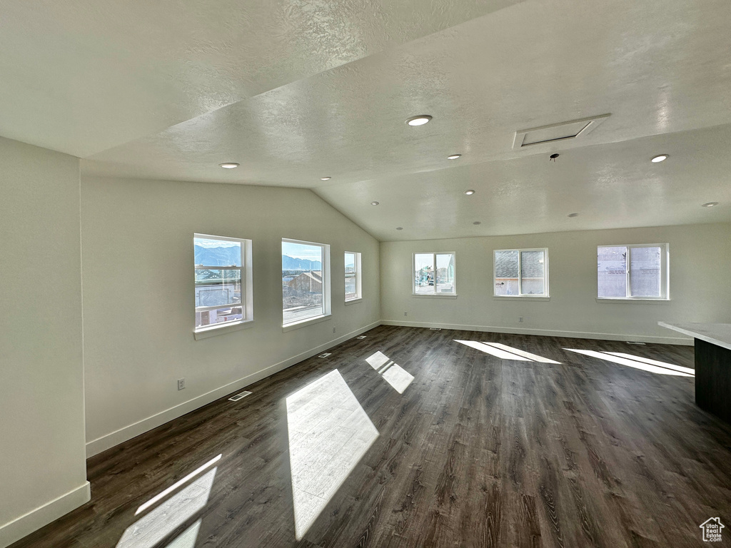 Interior space with a textured ceiling, lofted ceiling, and dark hardwood / wood-style flooring