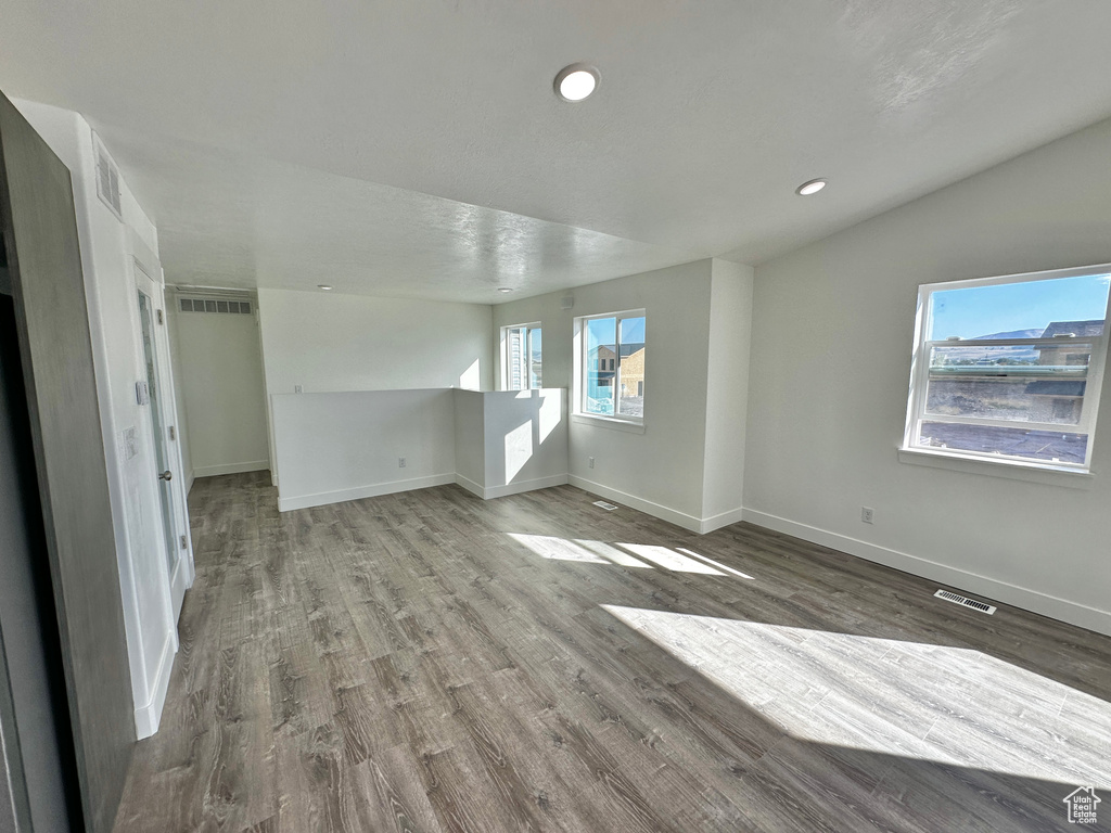 Unfurnished living room featuring lofted ceiling and wood-type flooring