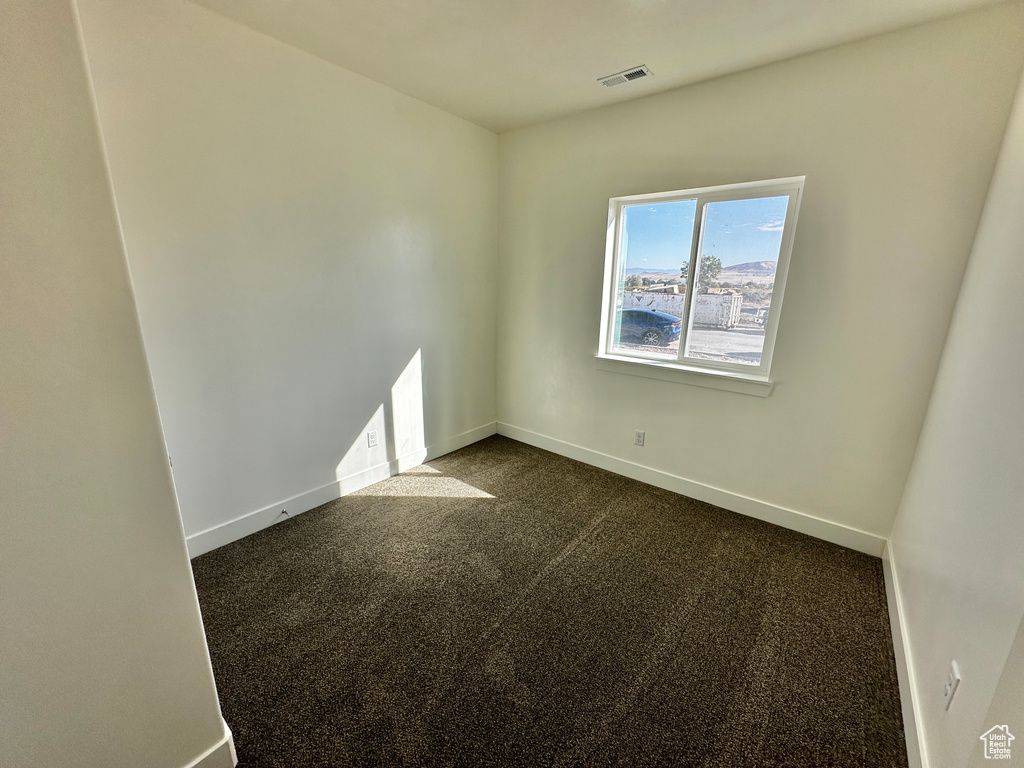 Spare room featuring dark carpet