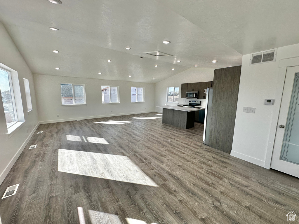 Unfurnished living room featuring vaulted ceiling and hardwood / wood-style floors