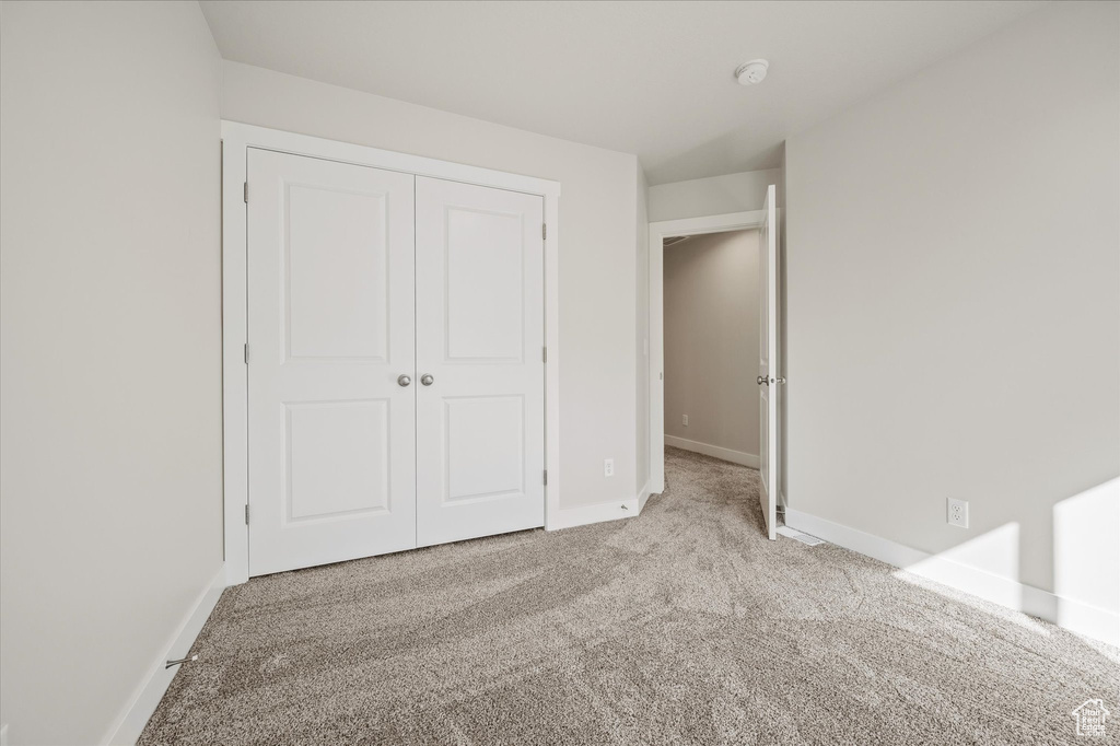 Unfurnished bedroom featuring a closet and light colored carpet