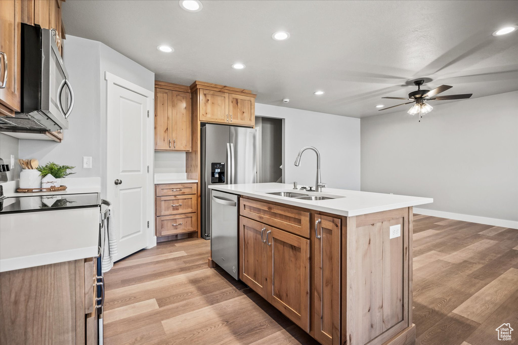 Kitchen with ceiling fan, sink, a center island with sink, light hardwood / wood-style flooring, and stainless steel appliances