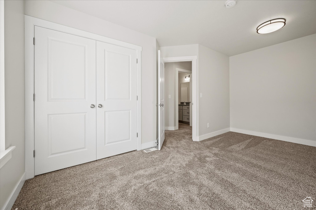 Unfurnished bedroom featuring light carpet and a closet