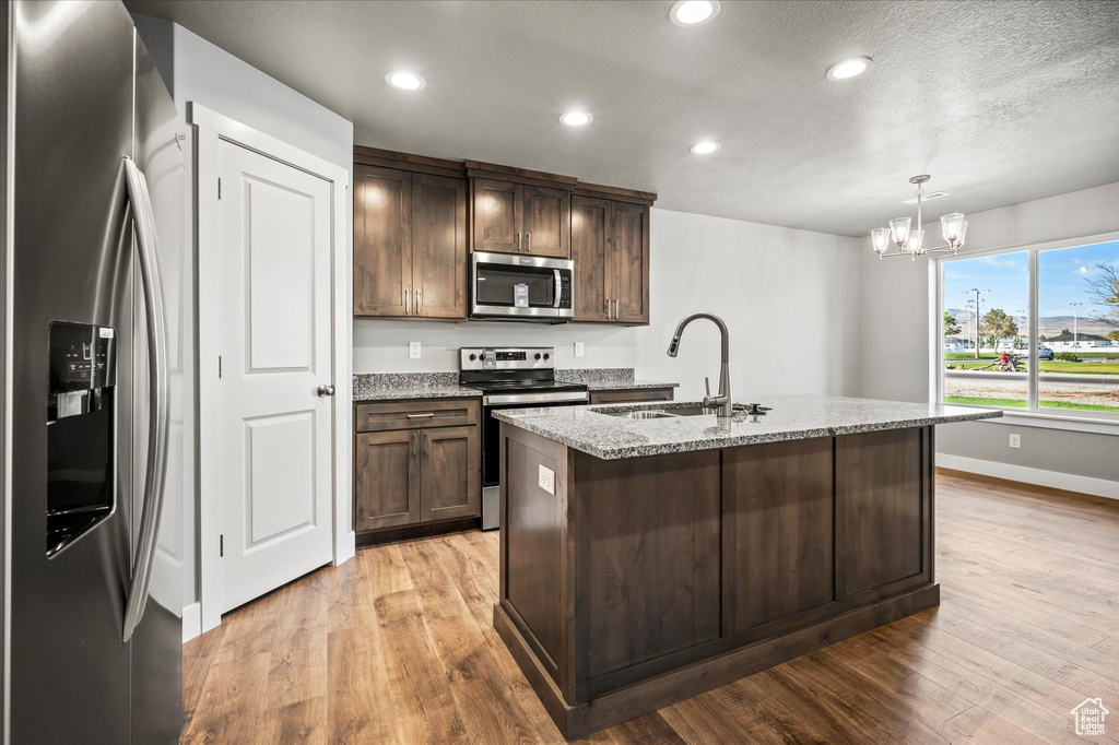 Kitchen featuring hanging light fixtures, sink, a center island with sink, a chandelier, and appliances with stainless steel finishes