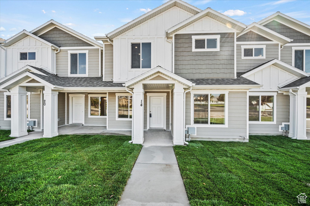 Multi unit property with board and batten siding, a front yard, and roof with shingles