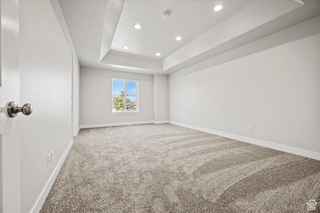 Empty room featuring a tray ceiling and carpet floors