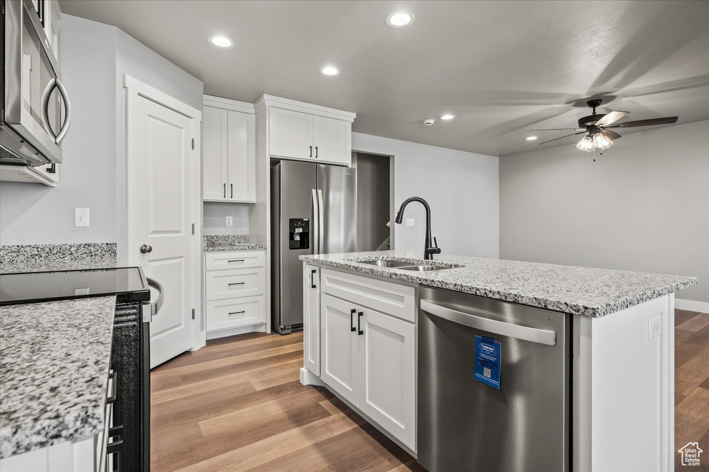 Kitchen featuring appliances with stainless steel finishes, light wood-type flooring, sink, and white cabinetry