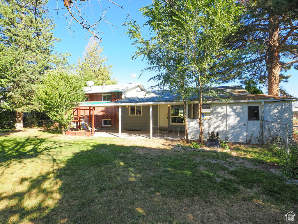 Rear view of property featuring a lawn and a patio area