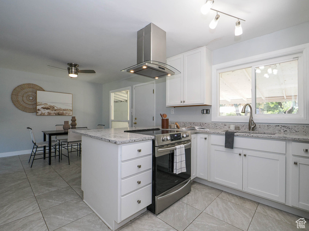 Kitchen with light stone counters, stainless steel electric stove, white cabinets, sink, and extractor fan