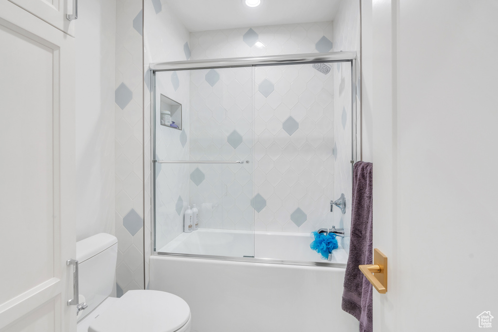 Bathroom featuring bath / shower combo with glass door and toilet