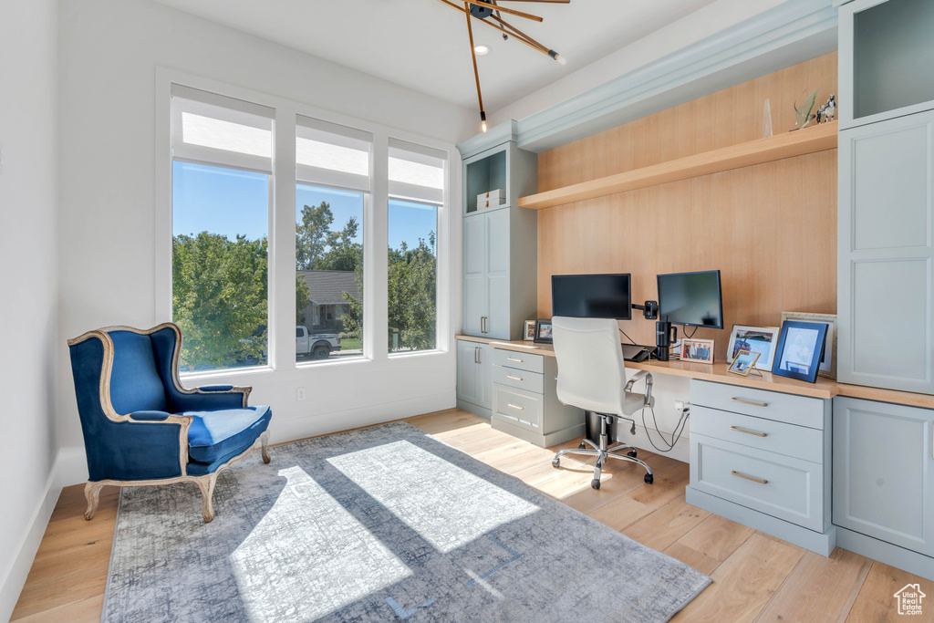 Home office featuring light wood-type flooring, built in desk, and ceiling fan