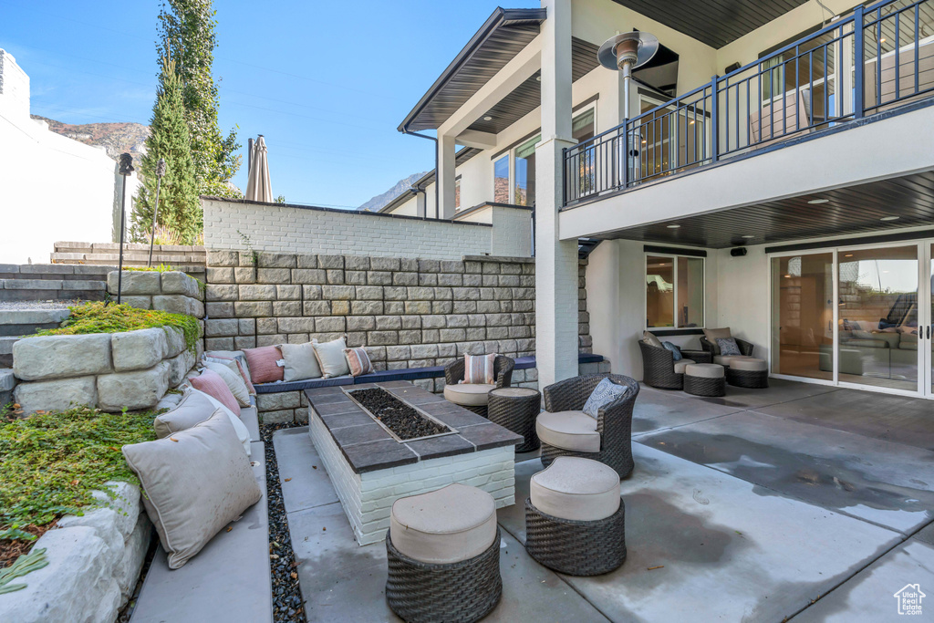 View of patio / terrace with a balcony and an outdoor living space with a fire pit