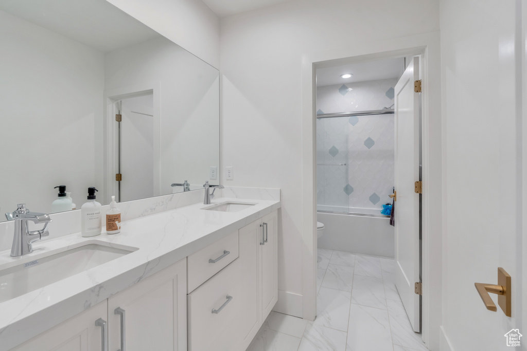 Full bathroom featuring vanity, toilet, and bath / shower combo with glass door