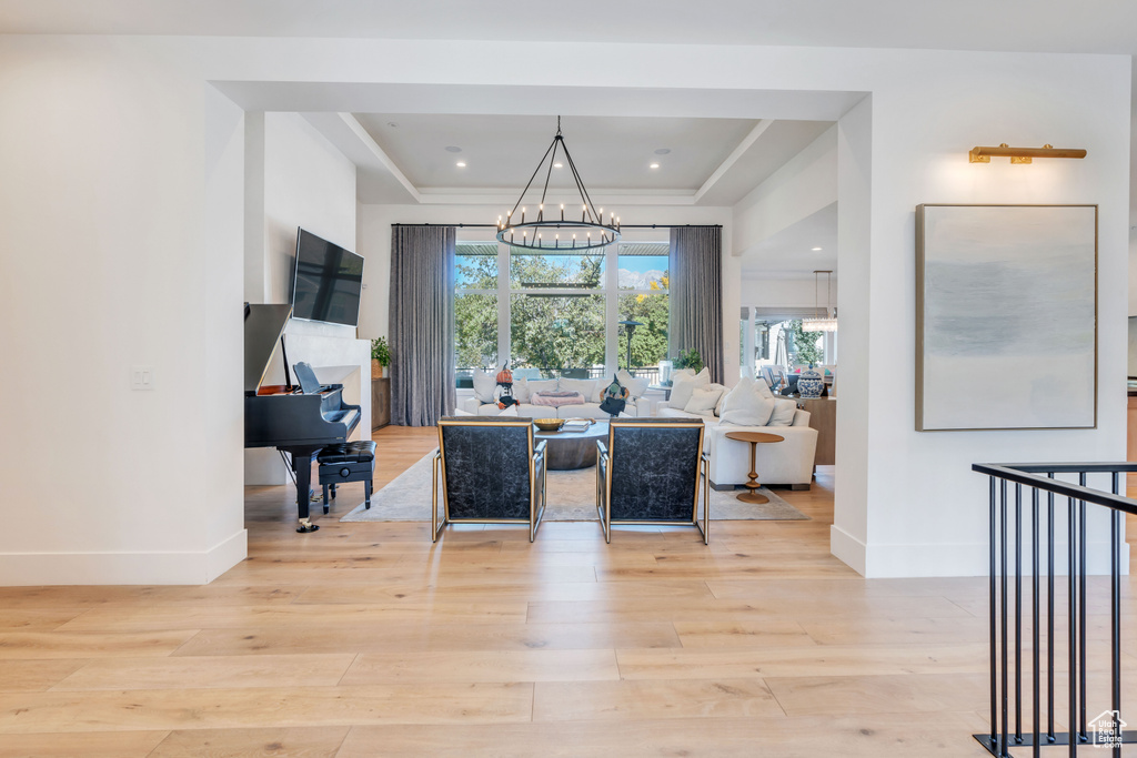 Dining room with light hardwood / wood-style flooring, a chandelier, and a tray ceiling