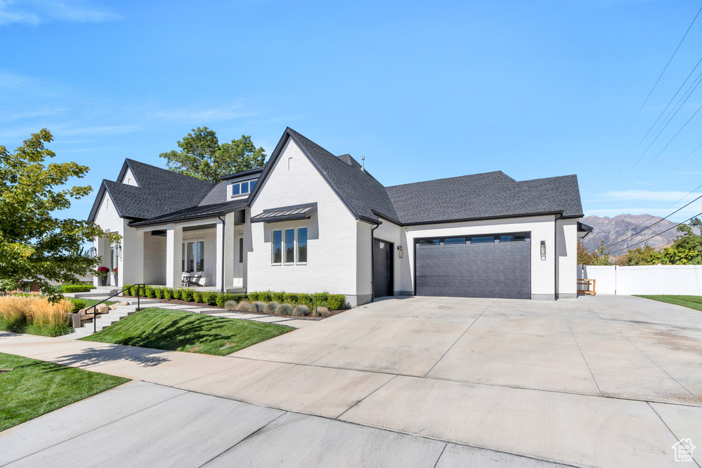 Modern farmhouse featuring a mountain view, a garage, and a front lawn