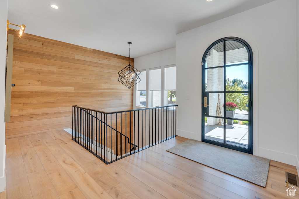 Entryway with wood walls, plenty of natural light, hardwood / wood-style floors, and a chandelier