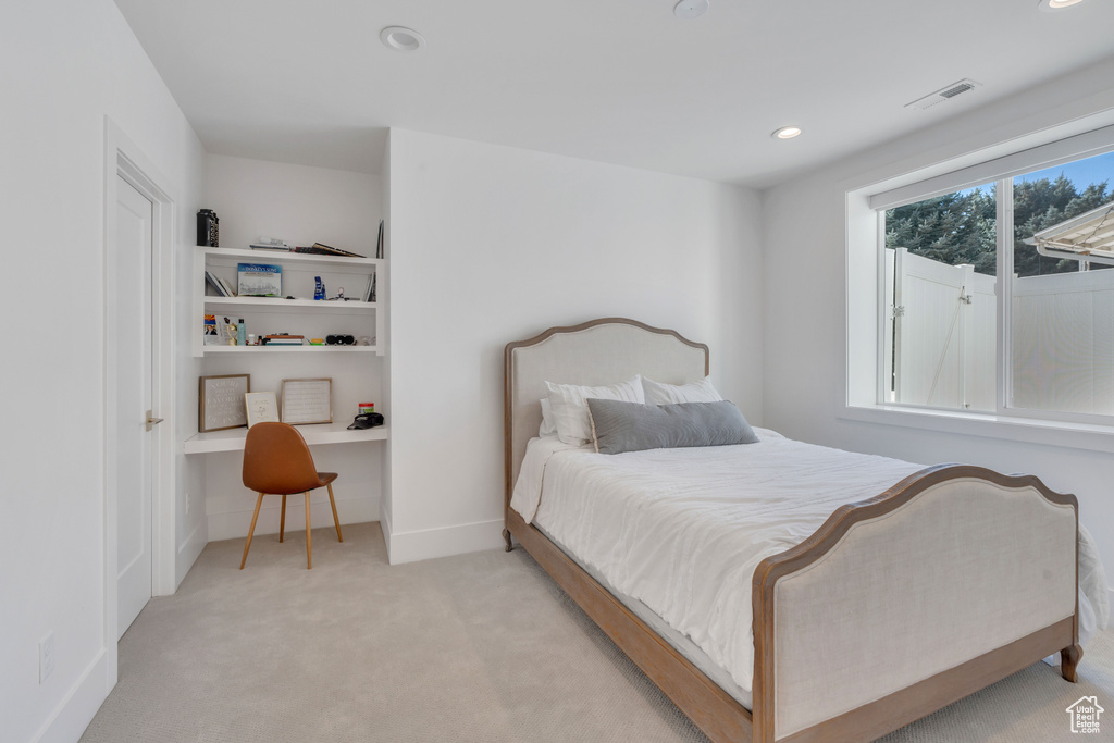 Carpeted bedroom featuring built in desk