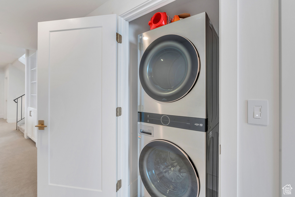 Laundry room featuring light carpet and stacked washer and clothes dryer