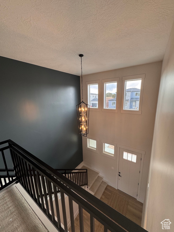 Stairway with parquet flooring, a chandelier, and a textured ceiling