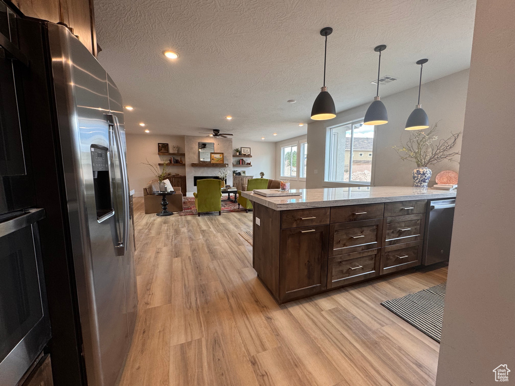 Kitchen featuring ceiling fan, decorative light fixtures, appliances with stainless steel finishes, and light hardwood / wood-style flooring