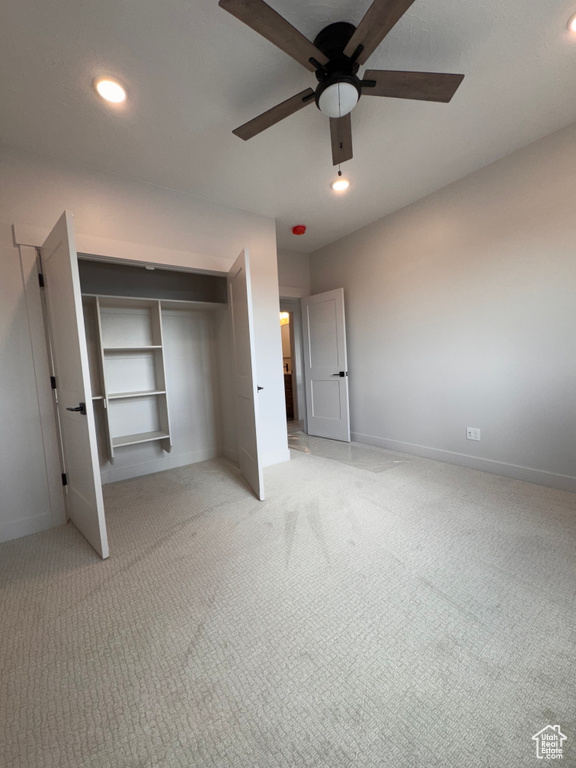 Unfurnished bedroom featuring a closet, light carpet, and ceiling fan