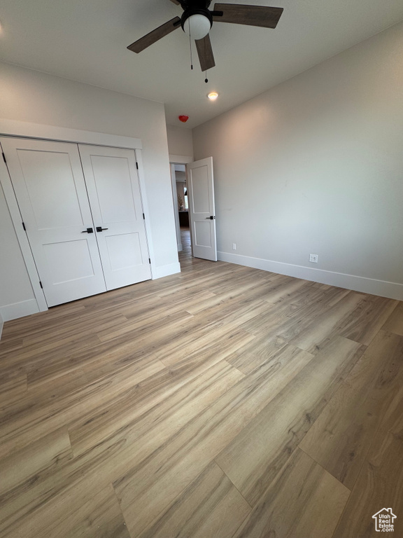 Unfurnished bedroom with a closet, light hardwood / wood-style floors, and ceiling fan