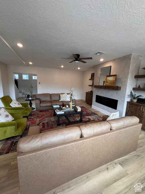 Living room with ceiling fan, light hardwood / wood-style floors, and a textured ceiling