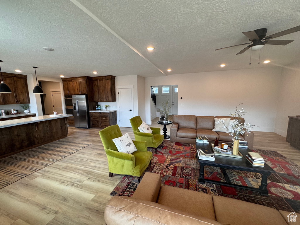 Living room featuring light wood-type flooring, ceiling fan, and a textured ceiling