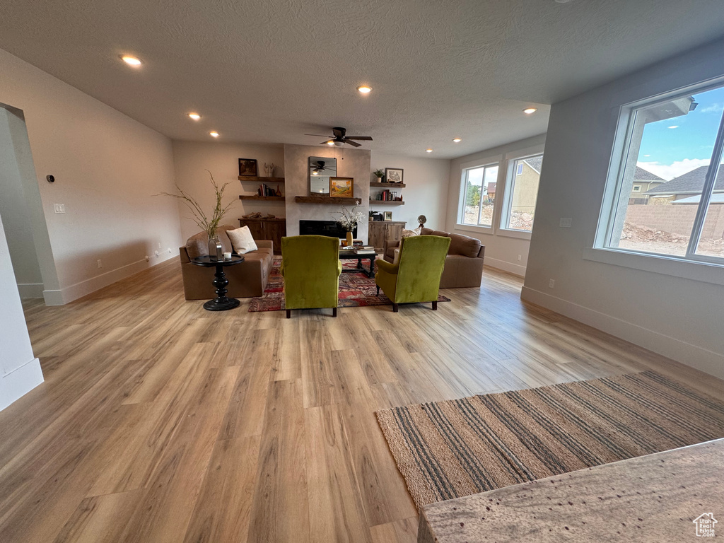 Living room with ceiling fan, light hardwood / wood-style flooring, and a textured ceiling