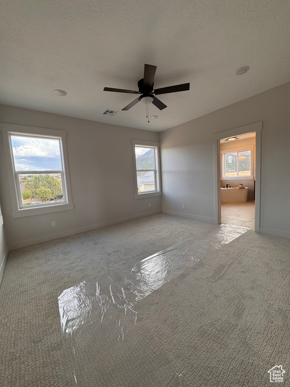 Carpeted empty room featuring ceiling fan and a textured ceiling