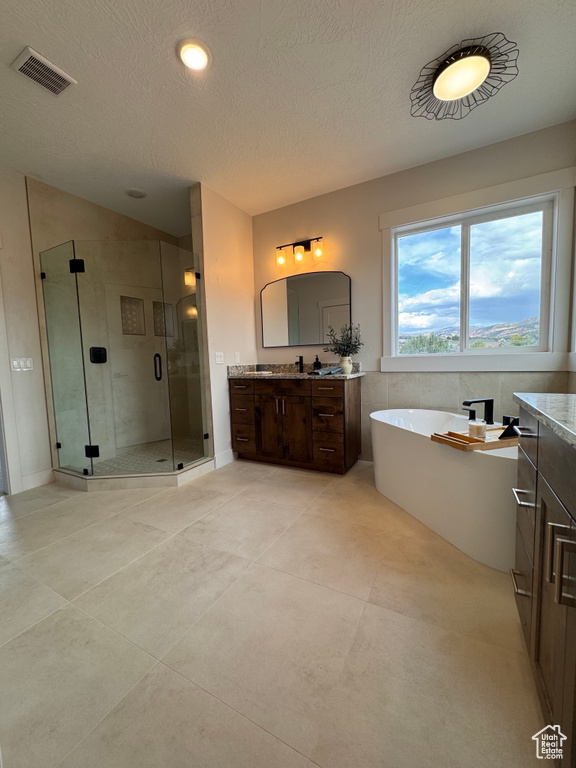 Bathroom featuring shower with separate bathtub, vanity, and a textured ceiling