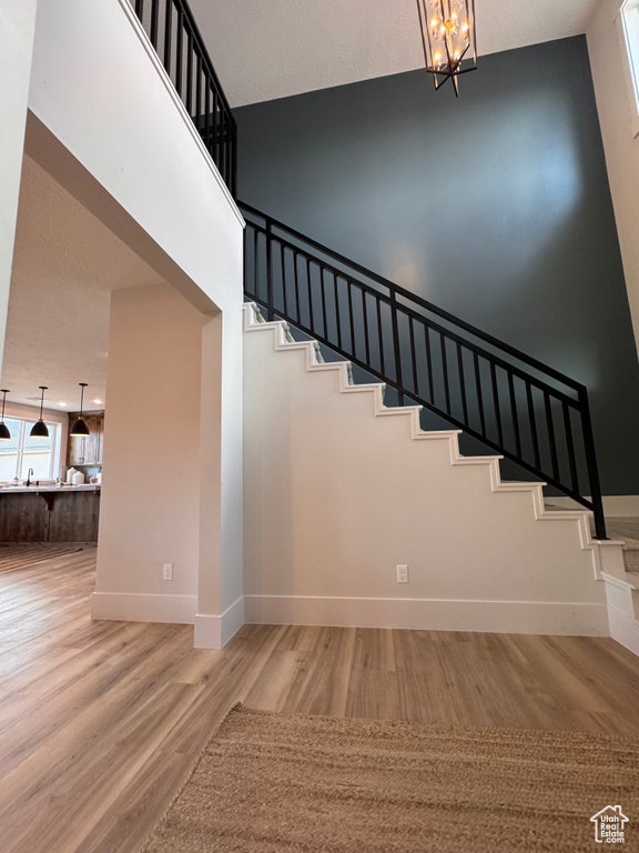 Stairway with a notable chandelier and wood-type flooring