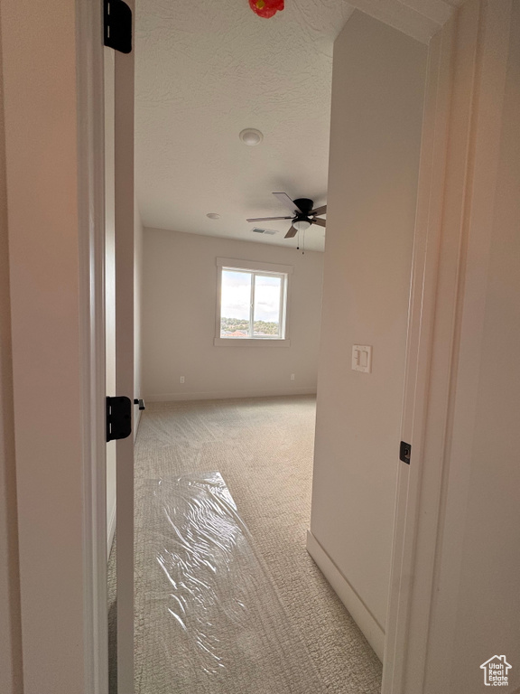 Spare room with light carpet, a textured ceiling, and ceiling fan