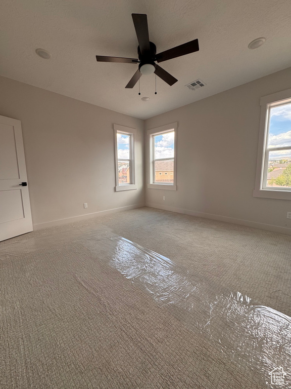 Unfurnished room with ceiling fan, a textured ceiling, and carpet flooring