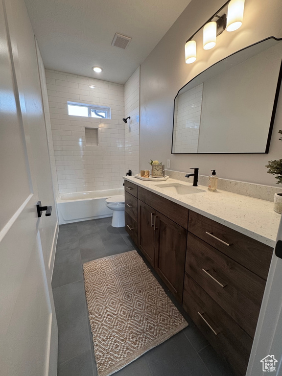 Full bathroom with tile patterned flooring, tiled shower / bath, vanity, and toilet