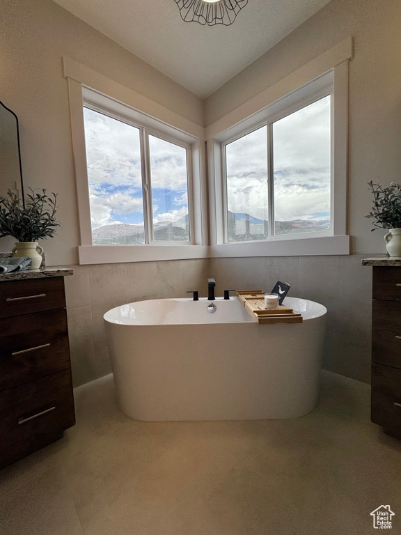 Bathroom featuring a bathtub, vanity, and tile walls