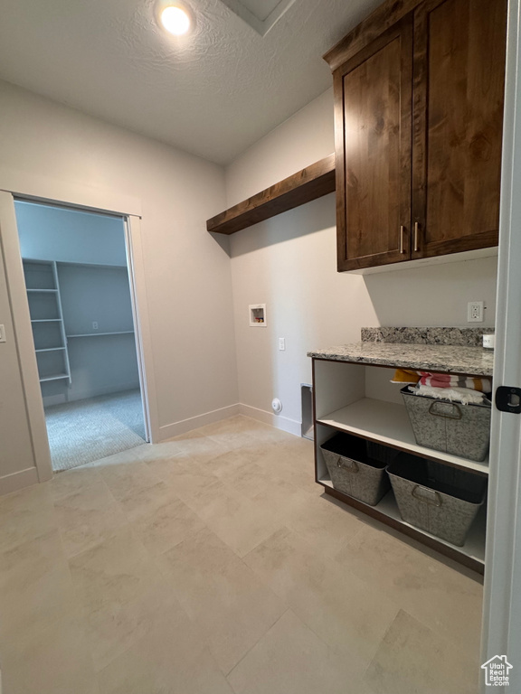 Washroom featuring a textured ceiling, hookup for a washing machine, and cabinets