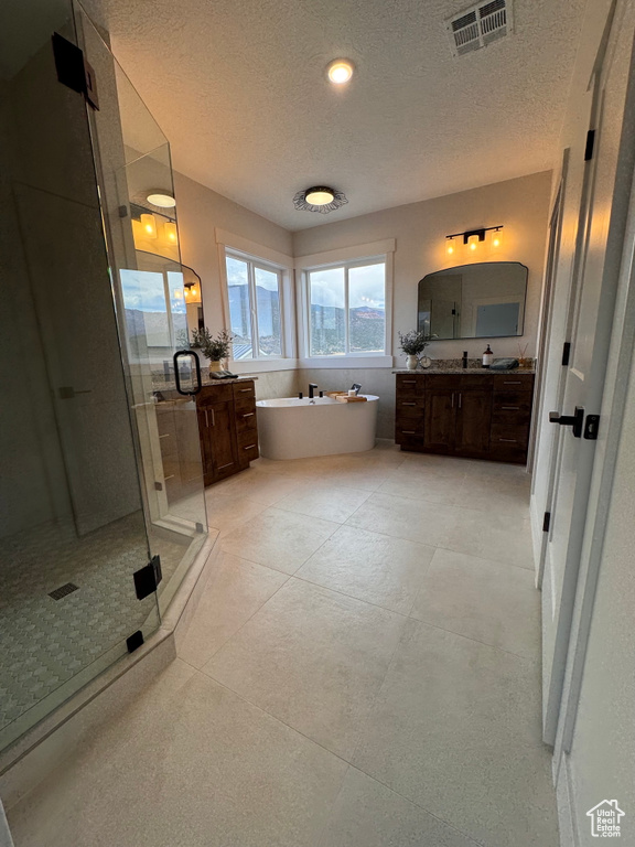 Bathroom featuring vanity, separate shower and tub, and a textured ceiling