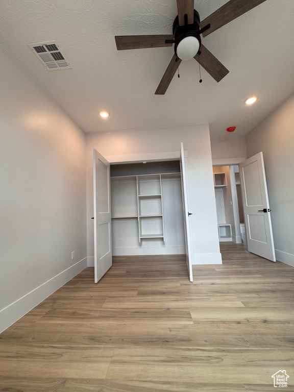 Unfurnished bedroom featuring ceiling fan, a textured ceiling, a closet, and light hardwood / wood-style flooring