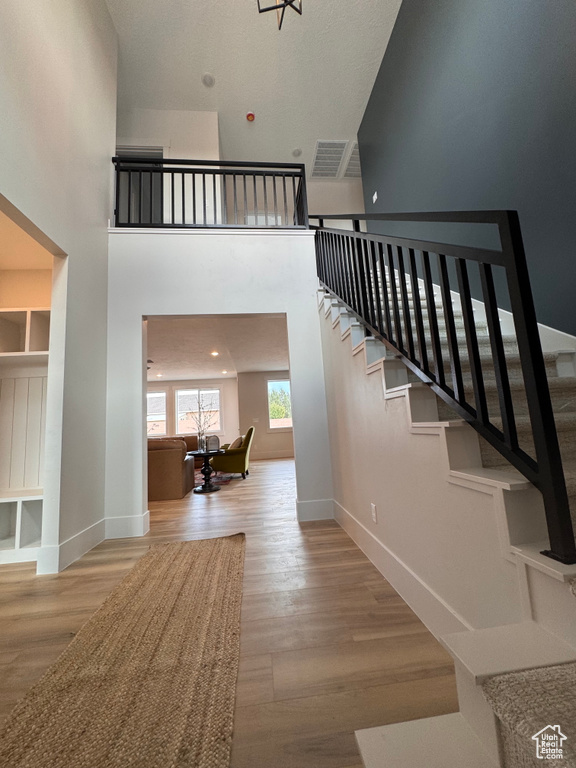 Stairway with a towering ceiling and wood-type flooring