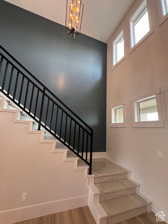 Staircase featuring an inviting chandelier, hardwood / wood-style flooring, and a towering ceiling