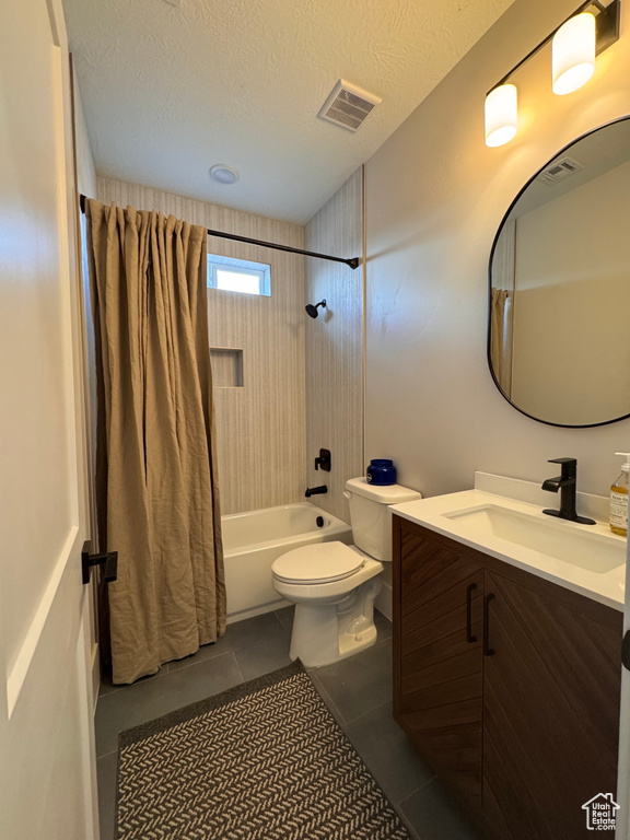 Full bathroom with toilet, shower / bath combo with shower curtain, tile patterned floors, vanity, and a textured ceiling