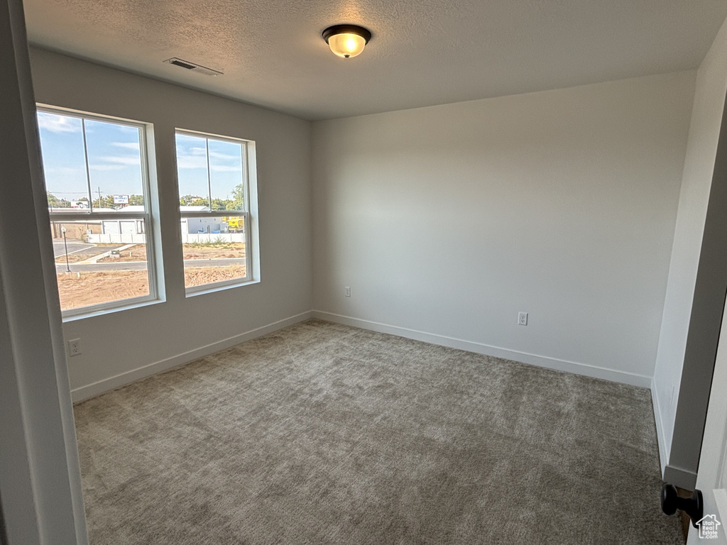 Carpeted empty room featuring a textured ceiling