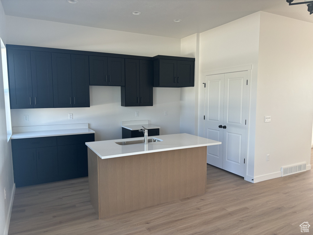 Kitchen with light hardwood / wood-style floors, a center island with sink, and sink