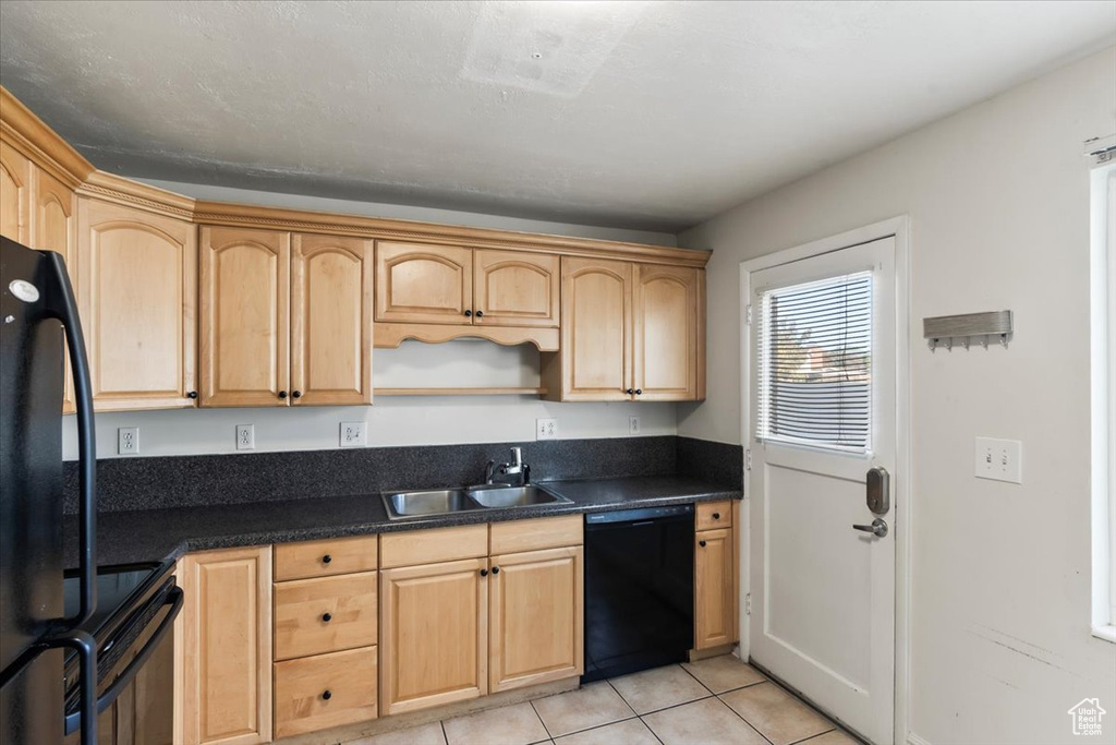 Kitchen featuring light tile patterned flooring, light brown cabinets, black appliances, and sink