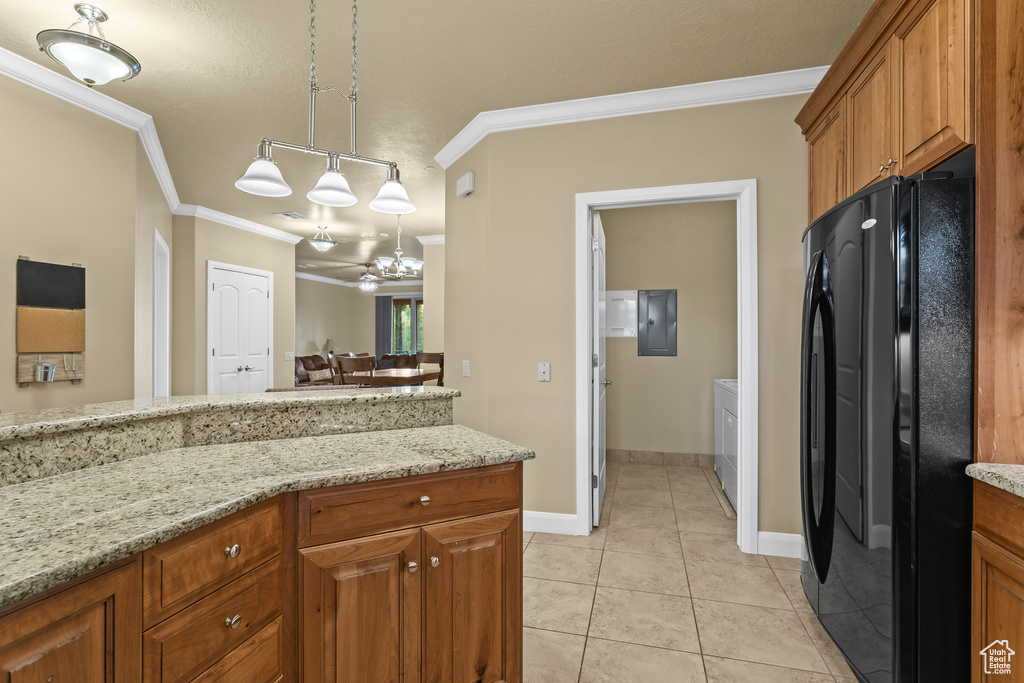 Kitchen with light tile patterned flooring, pendant lighting, crown molding, light stone counters, and black refrigerator