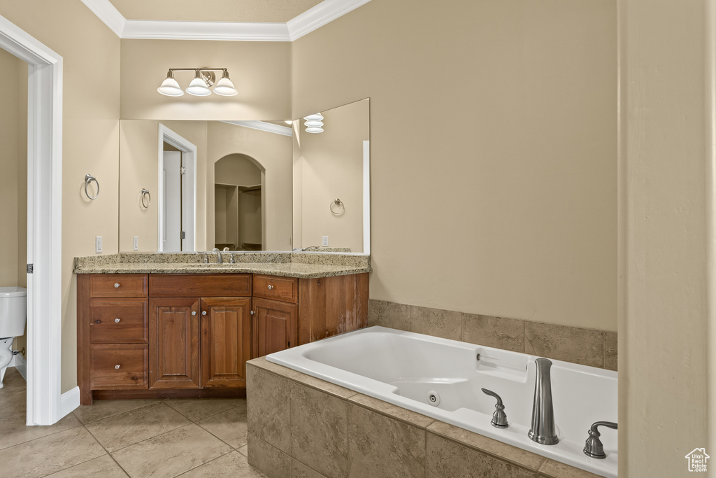 Bathroom featuring vanity, tile patterned floors, tiled bath, crown molding, and toilet