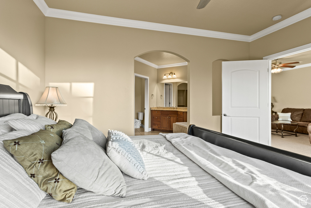 Bedroom with ornamental molding, ensuite bathroom, and ceiling fan