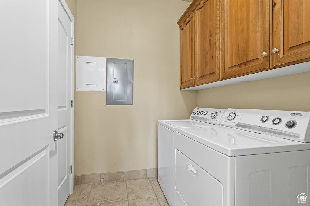 Washroom featuring cabinets, separate washer and dryer, and electric panel